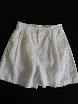 White wide-leg linen shorts laid flat, high waist with pleated front and belt loops