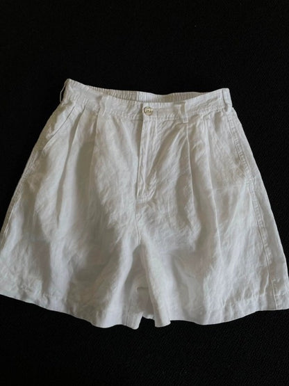 White wide-leg linen shorts laid flat, high waist with pleated front and belt loops