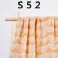Pure cotton muslin swaddle blanket rolled up, showing the airy gauze texture and printed design