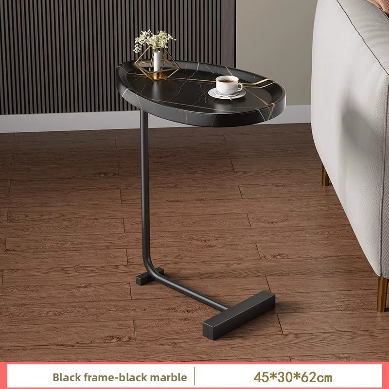 Modern C shaped side table with an oval top and metal frame styled in a living room corner