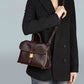 Woman in a black blazer wearing the coffee brown flap satchel across the body with the strap over one shoulder