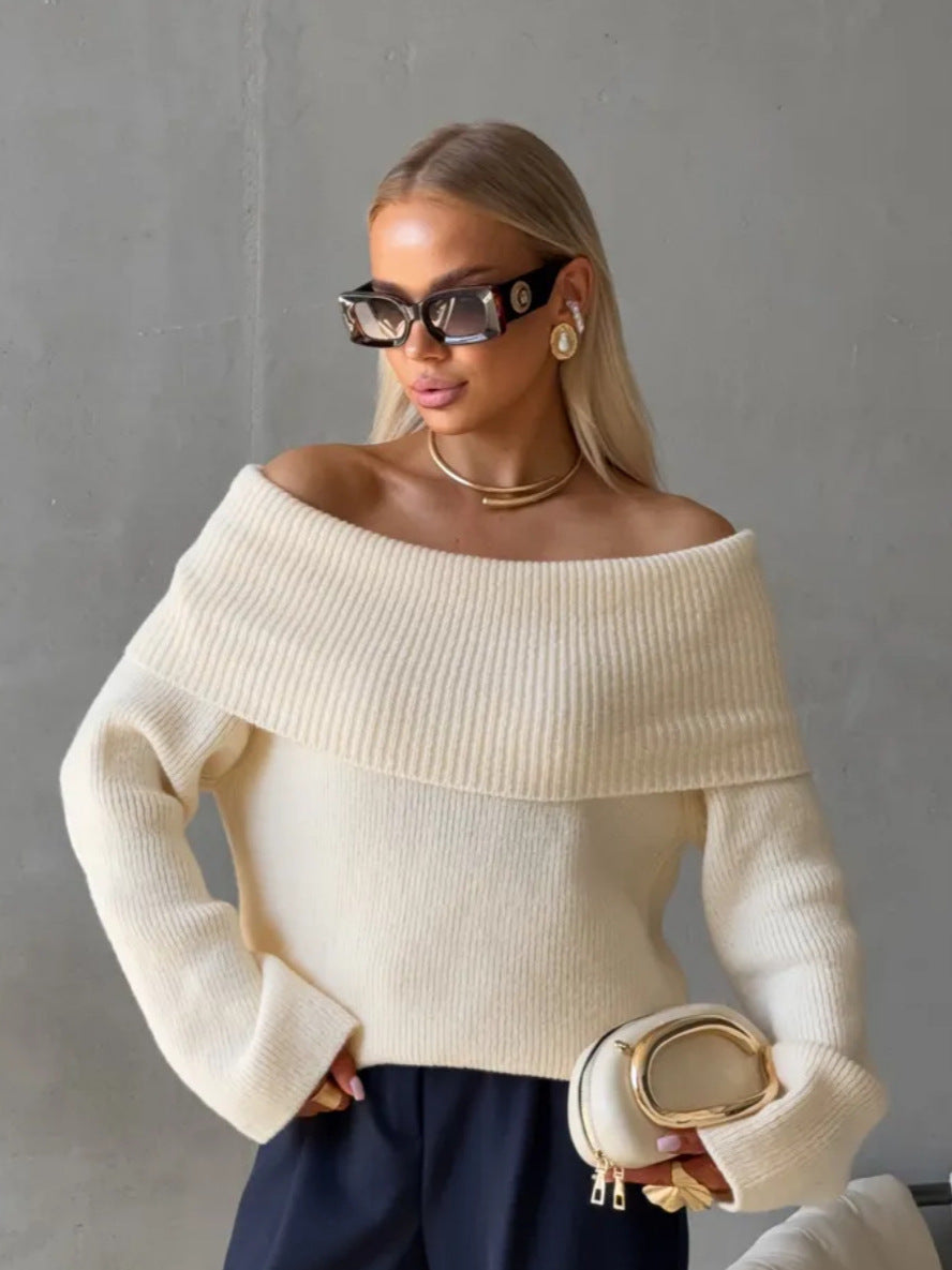Cream off-shoulder fold-over knit sweater with wide cuffs worn with navy trousers and a clutch