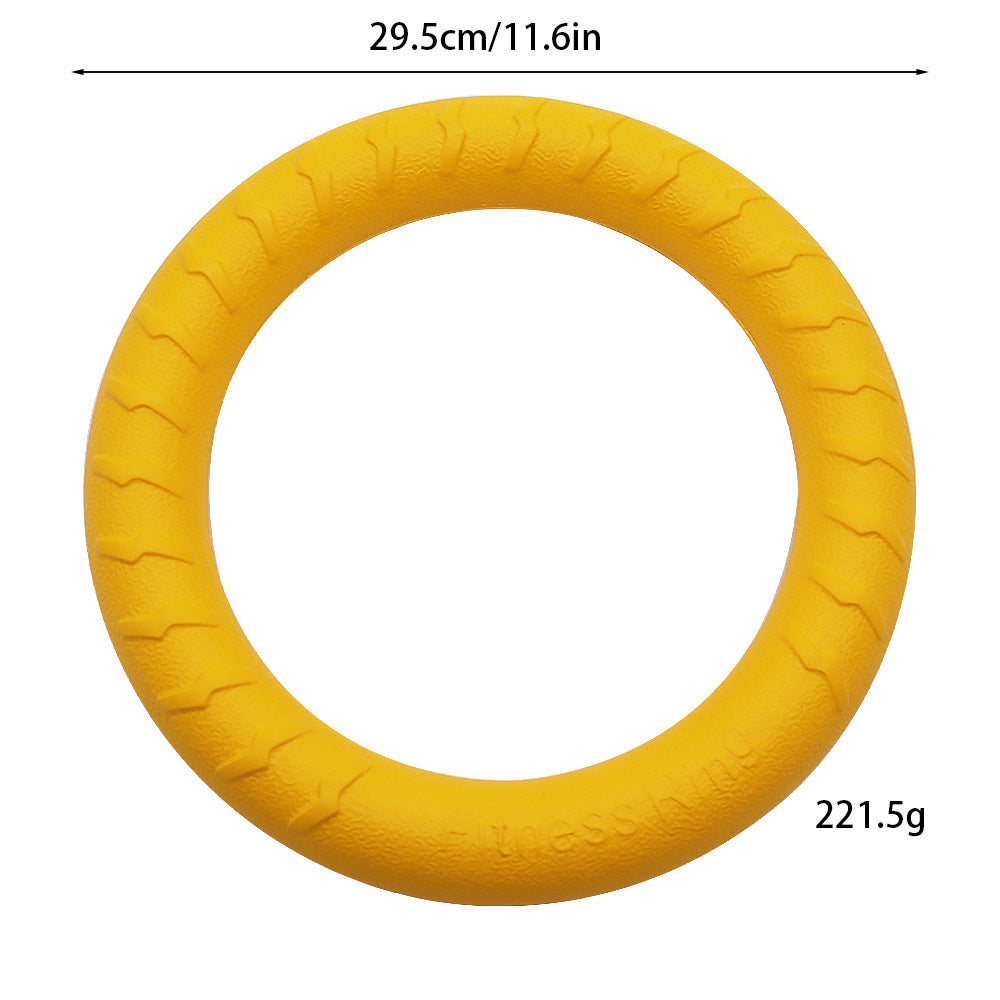 Yellow EVA foam dog fetch ring held by a black and white dog in a green yard