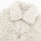 Close view of the cream curly fleece lapel collar and toggle fastener on a jacket