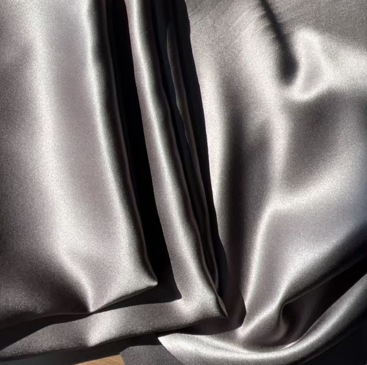 Mocha gray glossy silk pillowcases folded in smooth waves