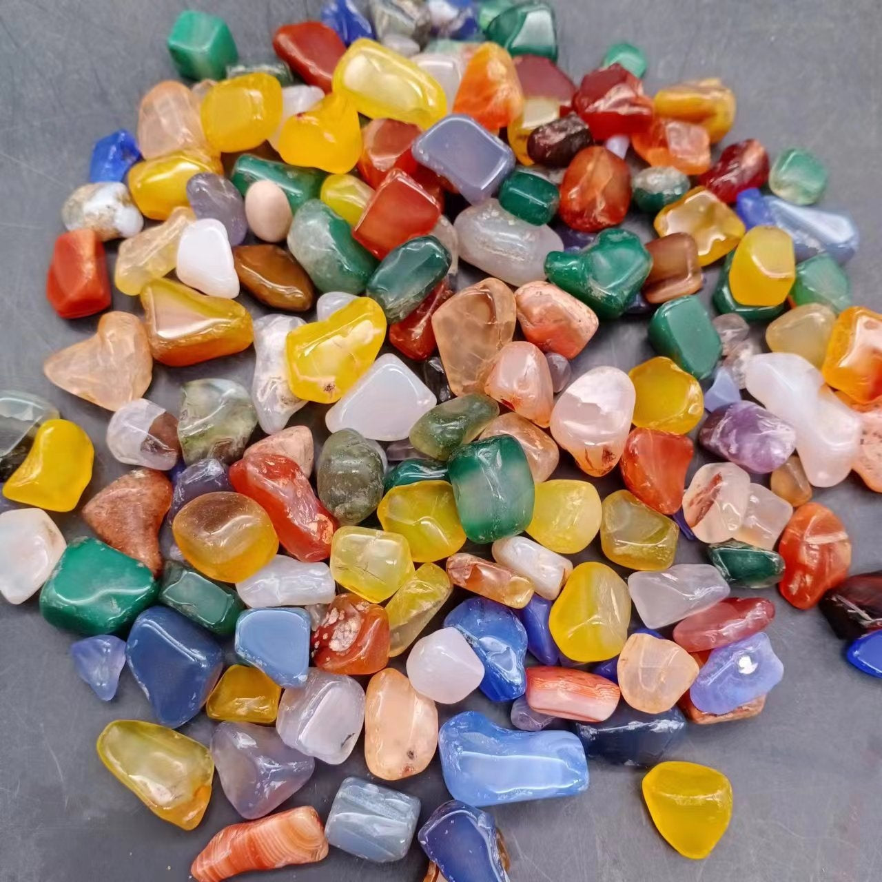 Yellow polished agate tumbled stones held in a hand for size reference