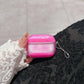 Pink marble AirPods protective cover case held in a hand near black fabric