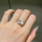 Platinum toned silver ring worn on a finger, clear oval stone and small white imitation pearl