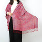 Woman holding out one end of a red paisley shawl showing the large paisley motif, border and red tassels