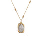 Two tone rose pendant necklace with gold frame and silver center laid on a light surface