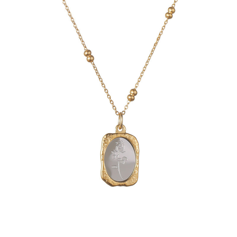 Two tone rose pendant necklace with gold frame and silver center laid on a light surface