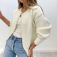 Woman wearing the cream faux pearl trimmed knit cardigan open over a white top and jeans