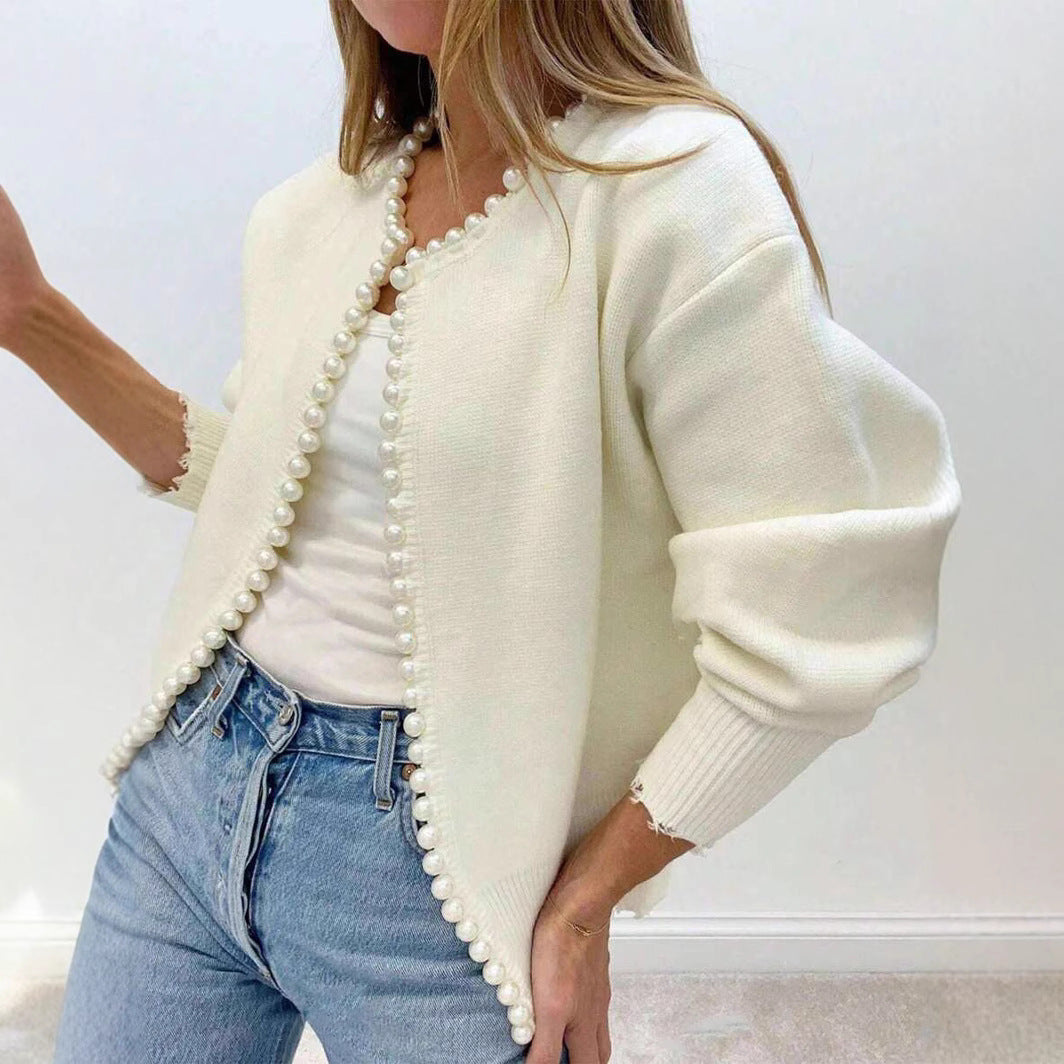 Woman wearing the cream faux pearl trimmed knit cardigan open over a white top and jeans