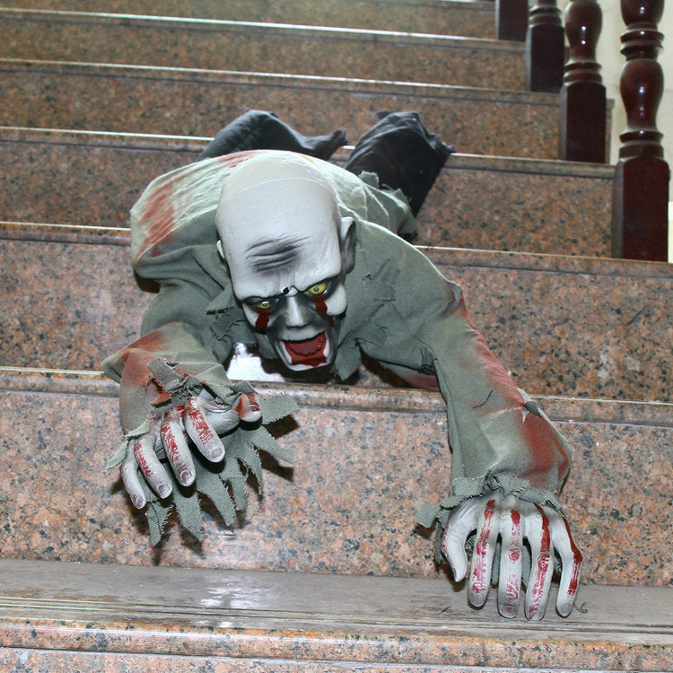 Crawling zombie prop posed on stone stairs reaching over a step with bloodied grey hands