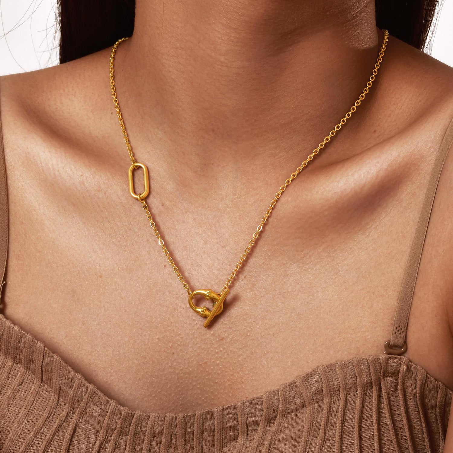 Gold tone toggle lariat necklace worn at the front over a plain neckline