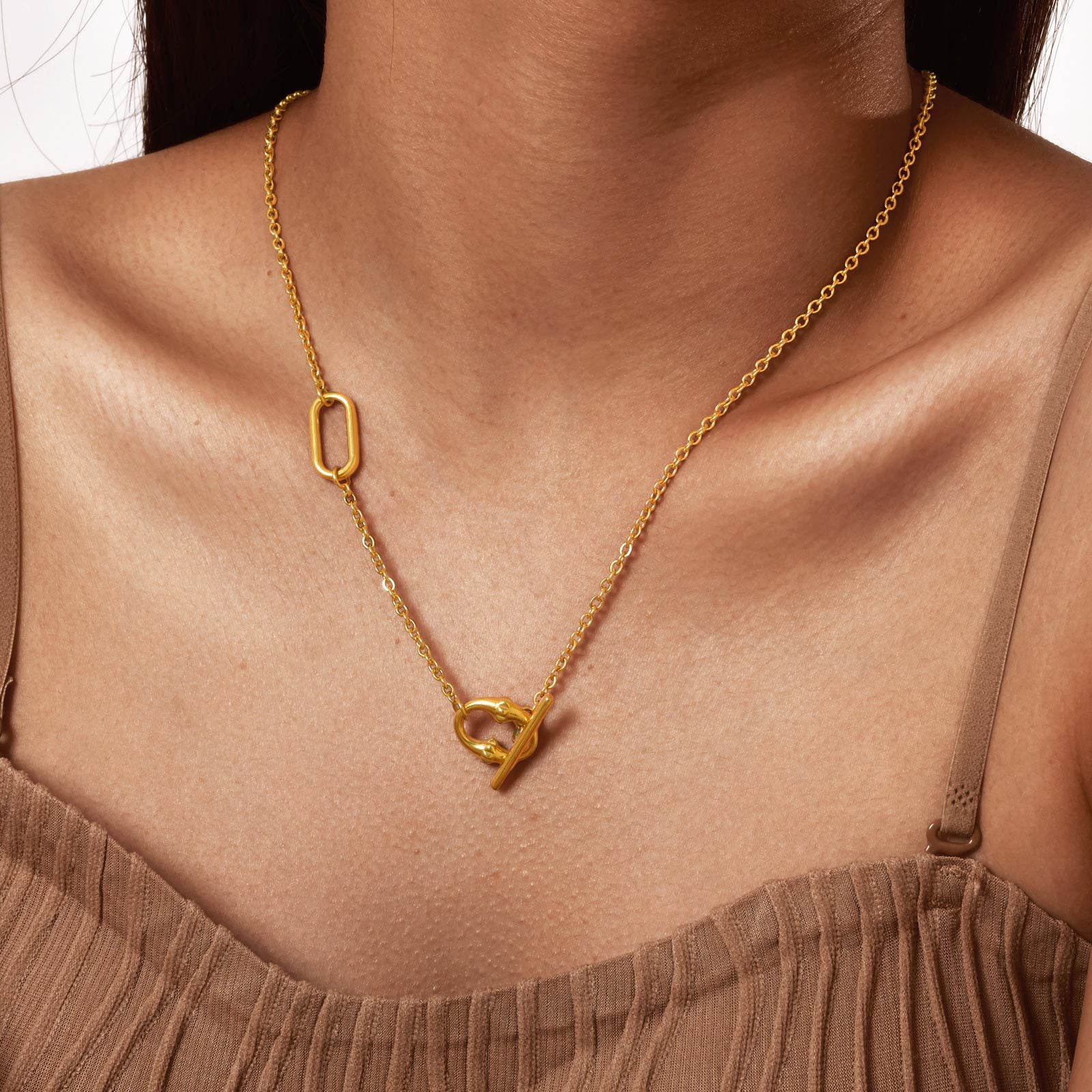 Gold tone toggle lariat necklace worn at the front over a plain neckline