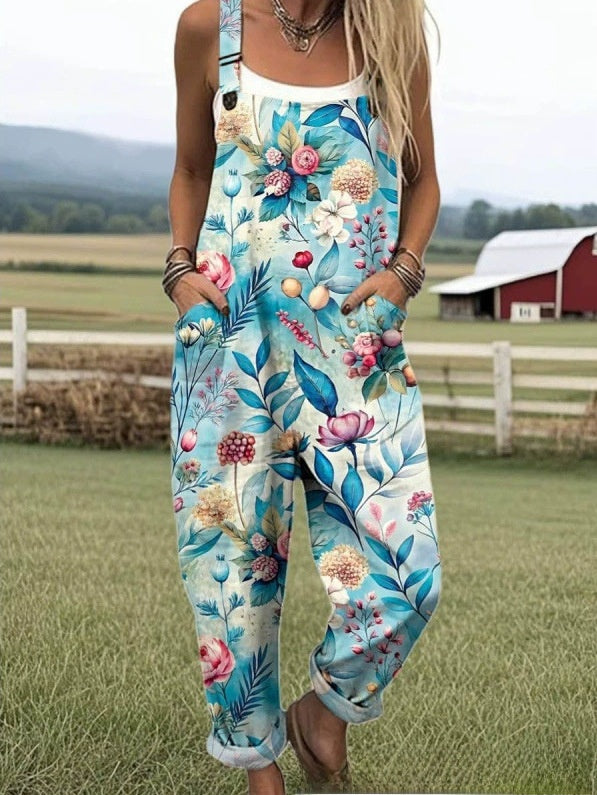 Size 3XL option: Aqua blue overalls with a pink and blue floral print, cuffed legs and pockets on a farm lawn