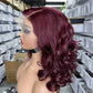 Wine red lace front wig seen from the right side, deep part and curls falling to the shoulder
