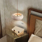 Natural travertine pendant shade with visible banding and open pores casting light up and down