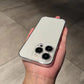 Back of a white iPhone in a clear hard case with a camera ring held in a hand