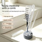 Clear comb with ball tipped teeth standing in a gray holder next to a dropper and a white dust cover