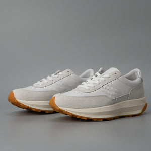 Pair of white leather low-top sneakers angled to show laces, suede toe and perforated side vent