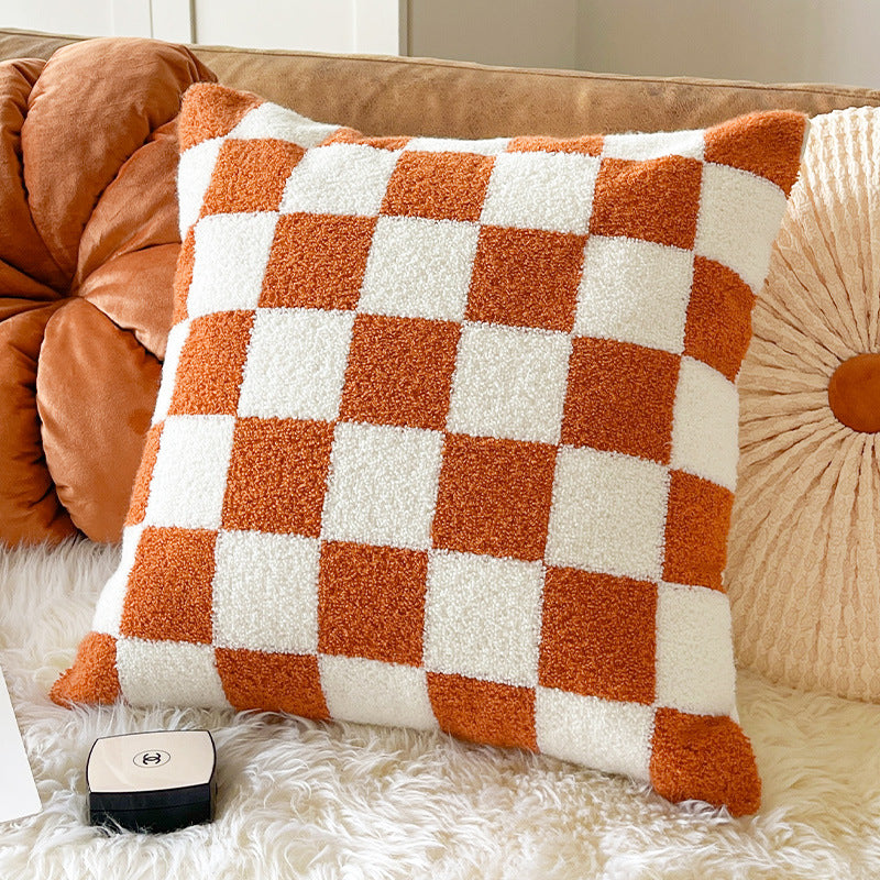 Orange and cream checkerboard plush throw pillow on a sofa beside a pumpkin pillow, throw pillow variant