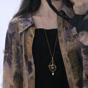 Armillary sphere pendant worn long over a black dress on a fine satellite chain