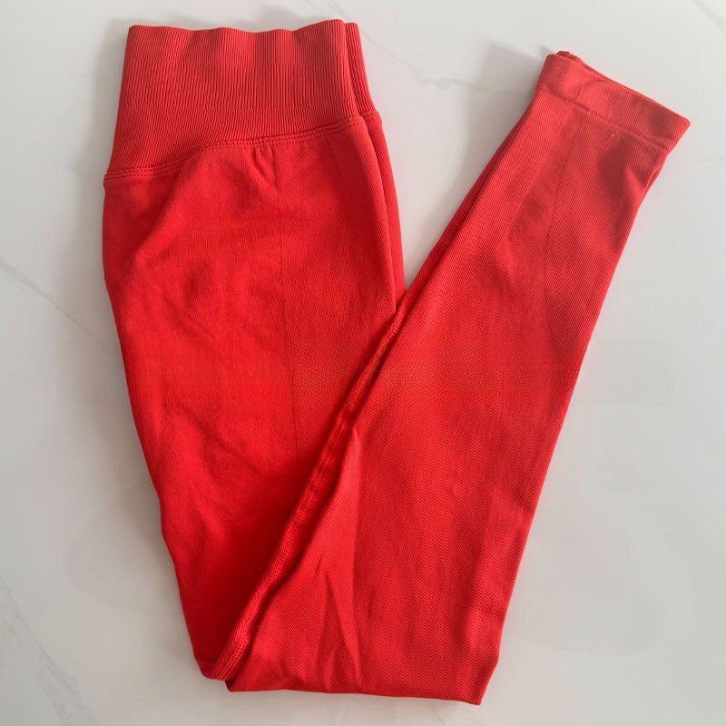 Chili red seamless yoga leggings folded flat, showing the tall ribbed waistband