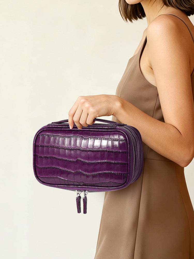 Woman carrying a purple crocodile pattern leather cosmetic bag with double zipper tabs hanging below
