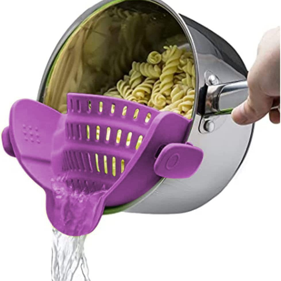 Purple silicone clip-on pot strainer, variant photo, clipped to a pot held by hand with water draining