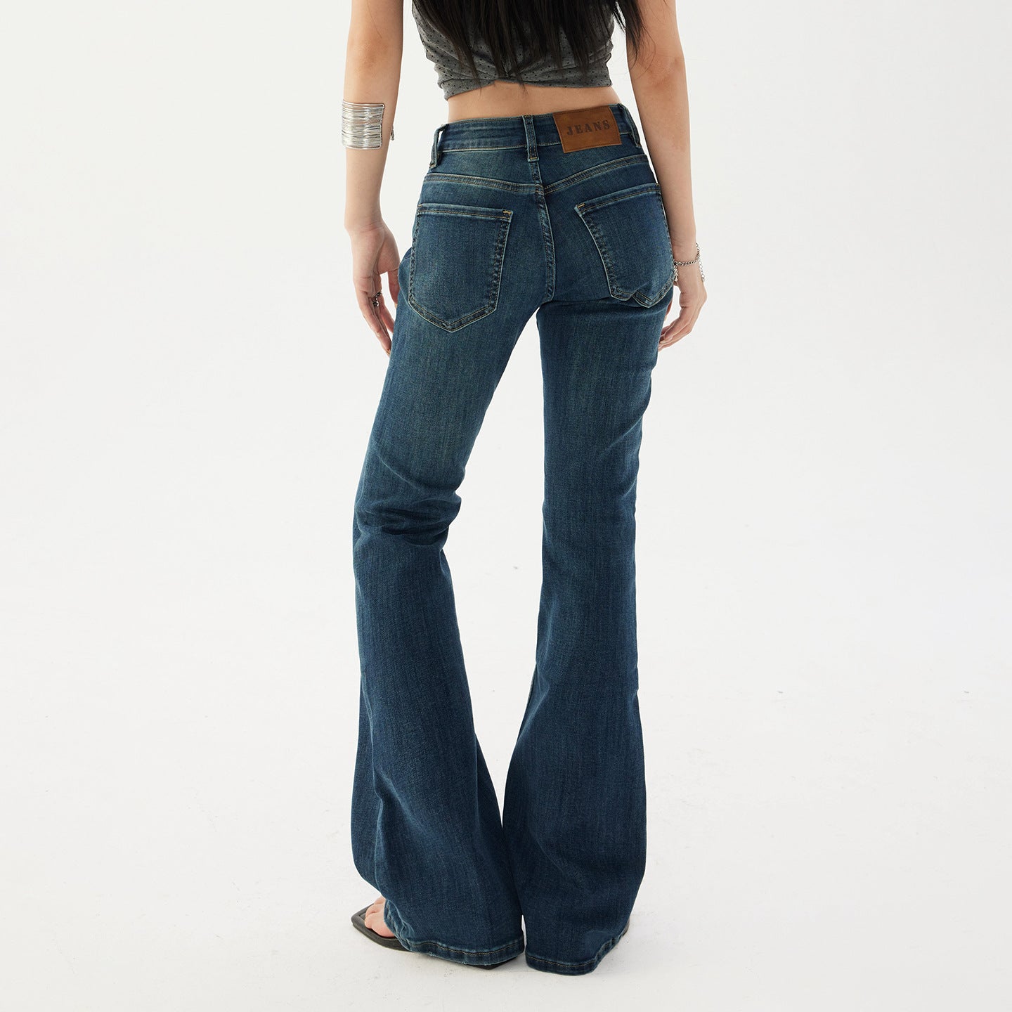 Back view of dark wash flared jeans showing two patch pockets, curved yoke and the flare below the knee