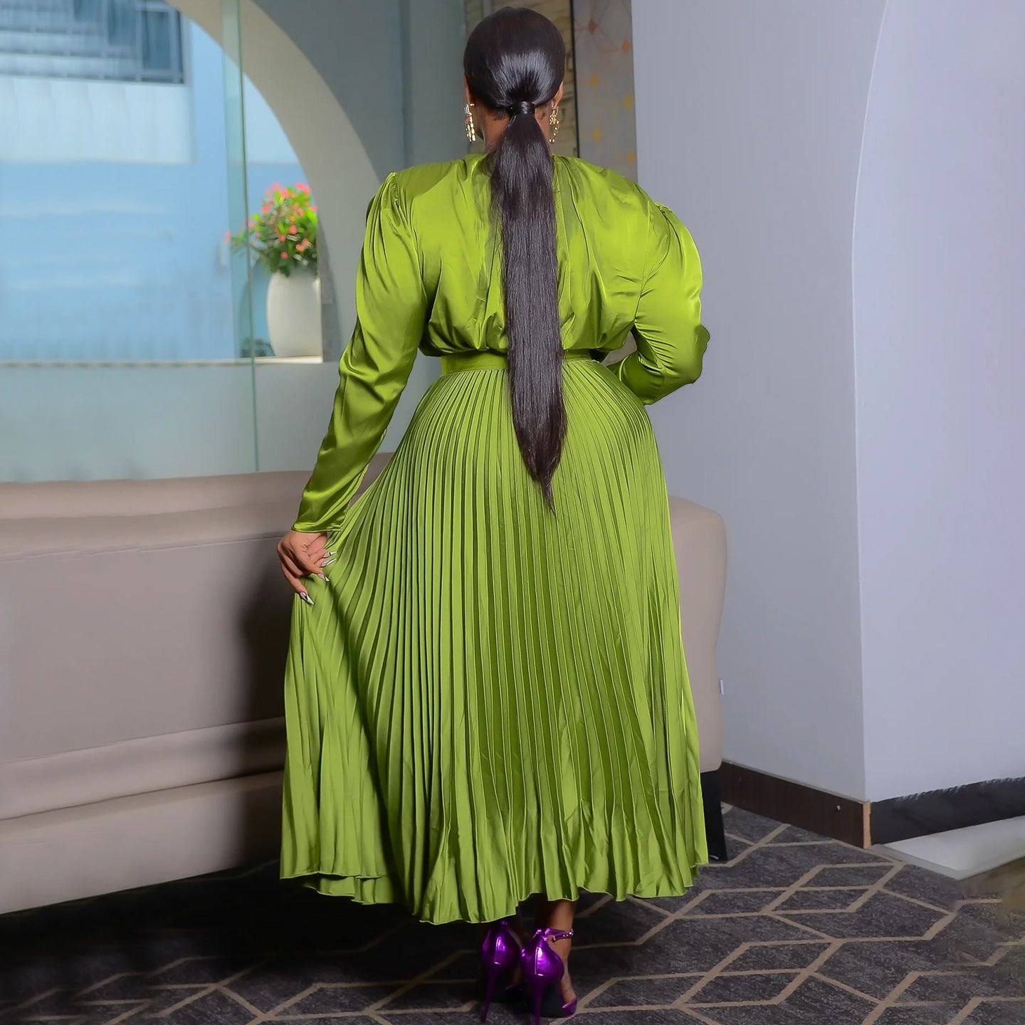 Olive green pleated maxi dress seen from the back, knife pleats falling from the belt