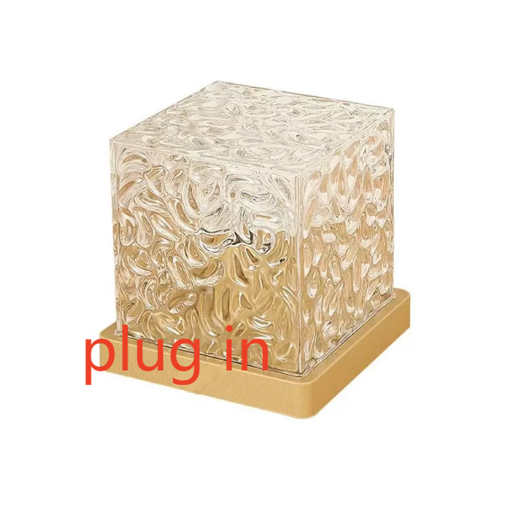 Clear rippled cube atmosphere lamp on a gold tone base projecting moving water light
