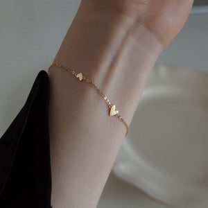 Heart-shaped bracelet front view, cast metal heart on a fine chain at the wrist