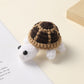 Crocheted brown and tan shell white turtle, handmade wool charm on a cream surface