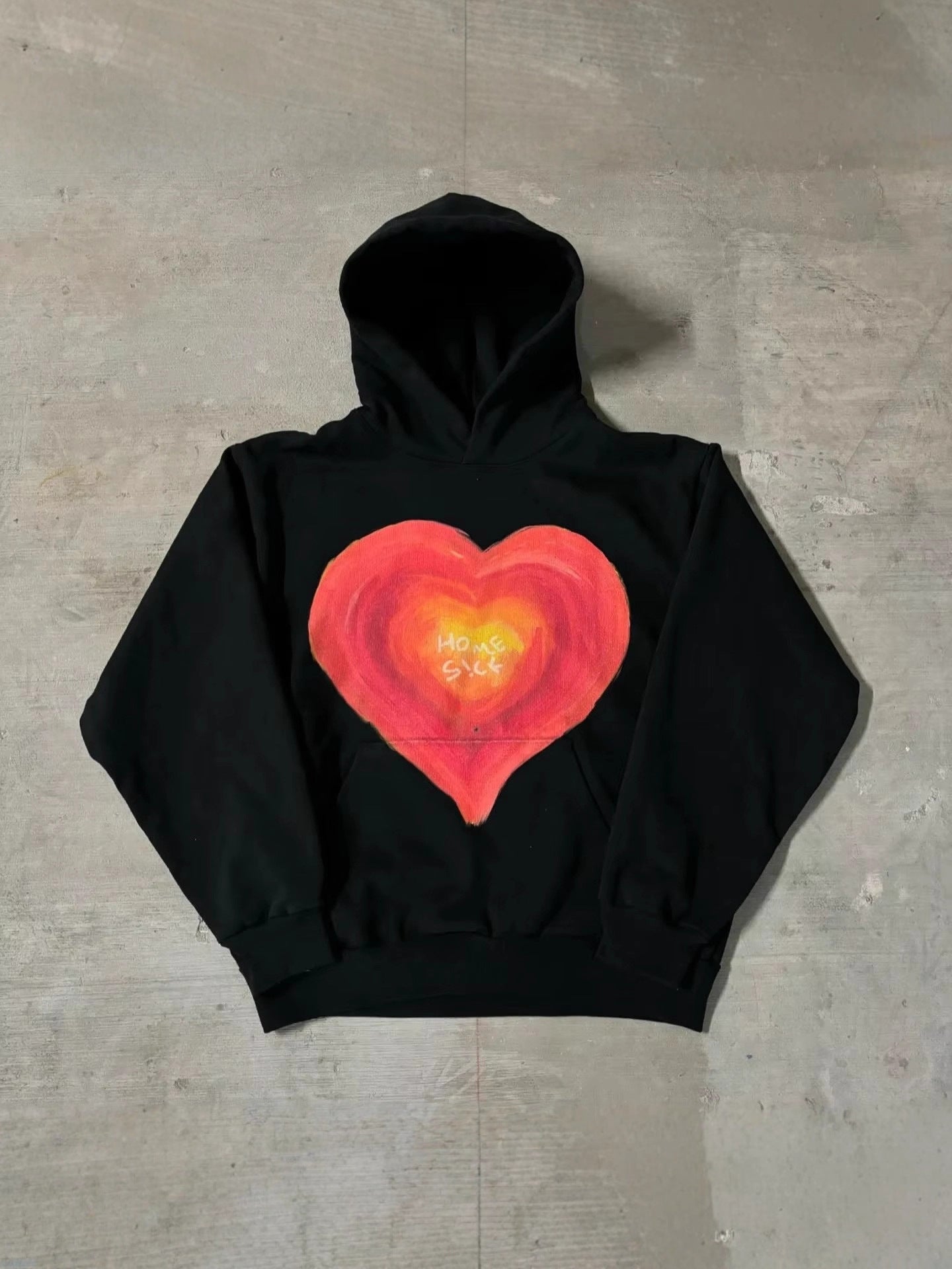 Black pullover hoodie with a hand painted Home Sick heart printed across the chest