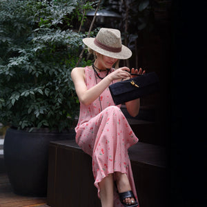 Woman seated in pink cherry gingham silk dress holding a black clutch