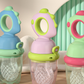 Infant holding the dinosaur fresh food feeder by the ring handle while gumming the pouch