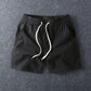 Black men's cotton drawstring shorts laid flat with the drawstring untied