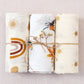 Large cotton muslin gauze baby blanket laid out, showing the loose breathable weave and print