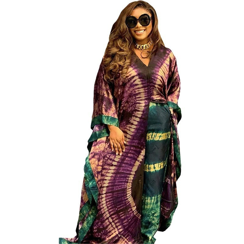 Model wears the purple and green tie dye satin caftan gown with a self tie side waist