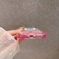 Bottom edge of a pink gradient clear case, speaker cutouts and charging port opening in view