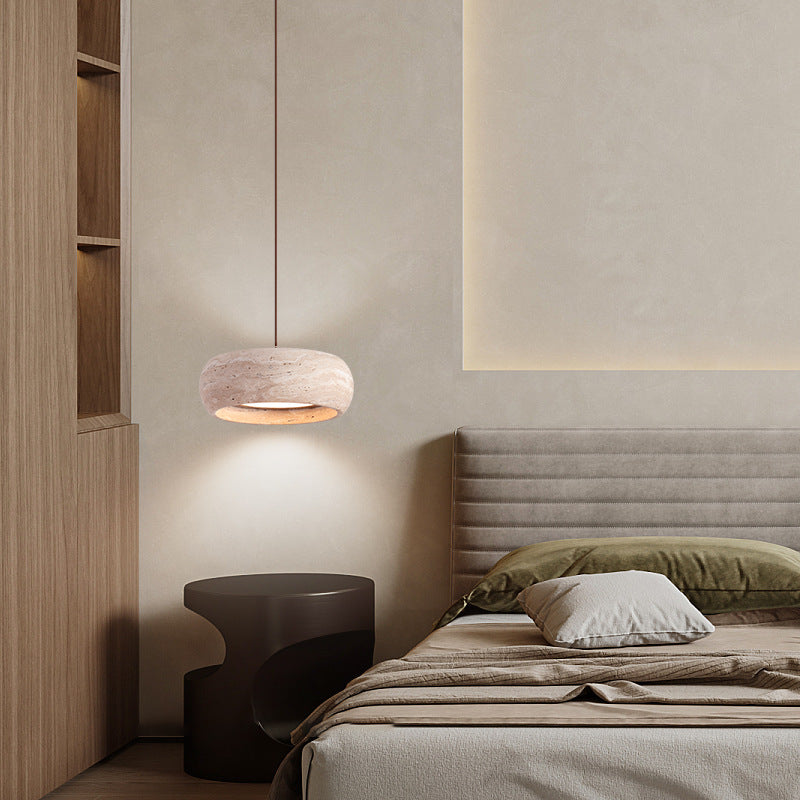 Rounded travertine stone pendant light on a slim cord in a warm neutral bedroom corner