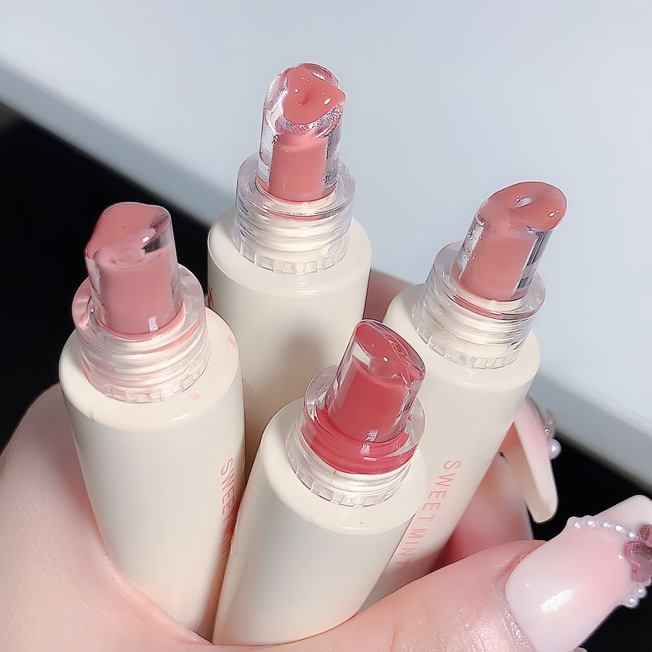 Cream lip glaze tubes with rounded glossy applicator tips shown in soft rosy nude shades