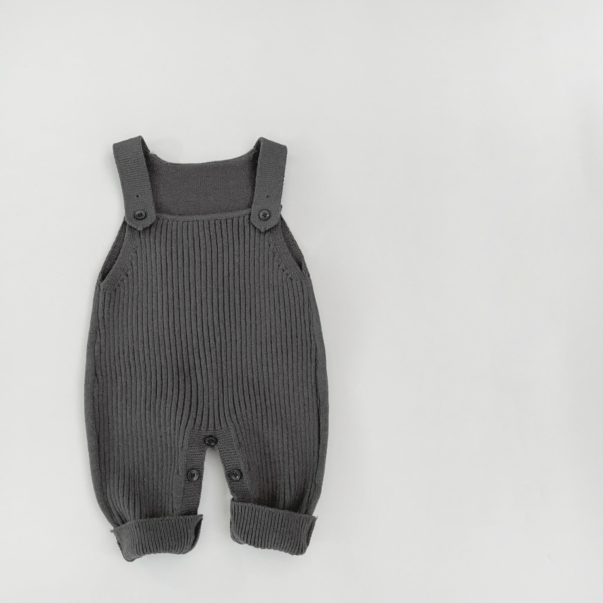 Soft focus lifestyle hero of the knit baby dungarees in a nursery