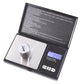 Open pocket scale with a round calibration weight on the platform, display labeled 1000 g capacity and 0.1 g