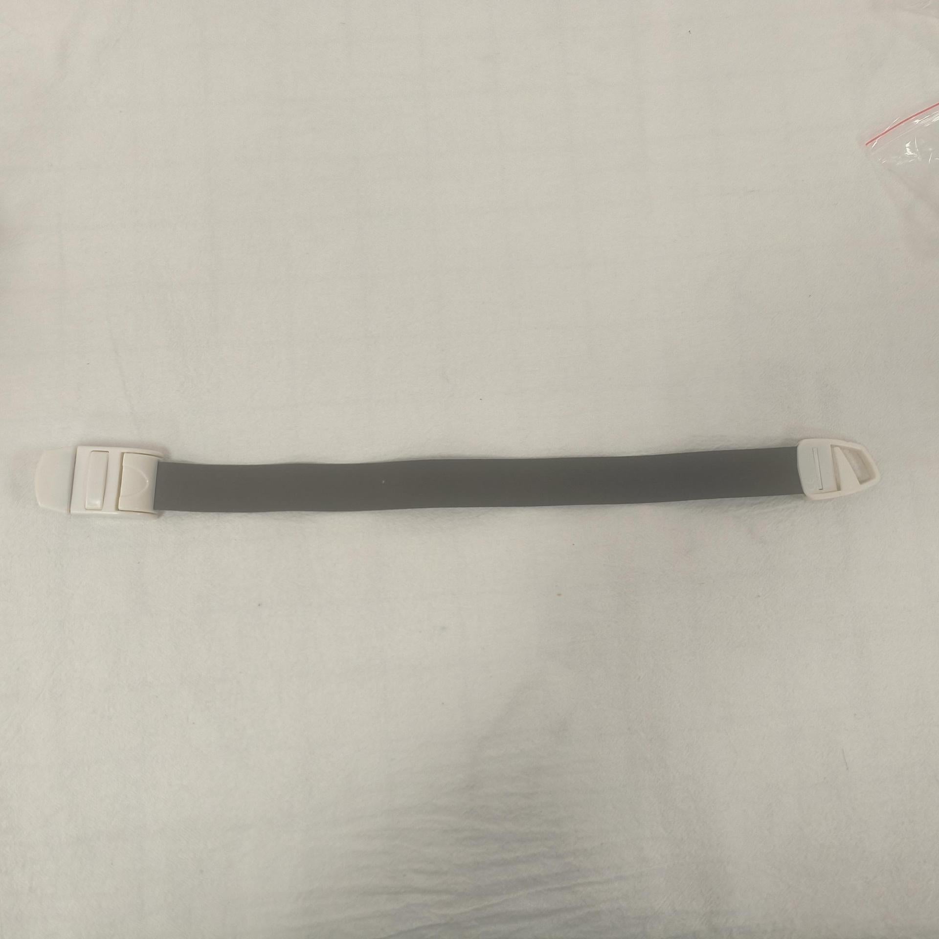 Single grey toned elastic quick release tourniquet band with a white snap buckle laid flat