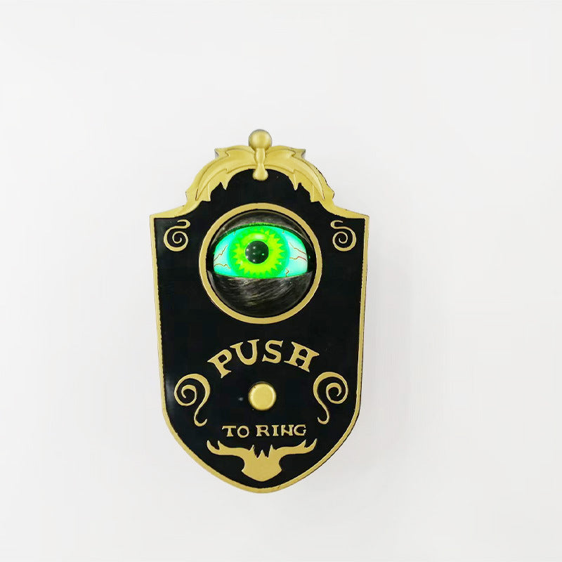 Black push to ring Halloween doorbell plaque with gold trim and a glowing green eyeball above the button