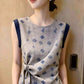 Upper view of the round neckline and navy shoulder trim on the sleeveless blouse